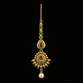 Gold necklace with red stones and a pearl on a dark background, featuring the brand 'Saheli'.