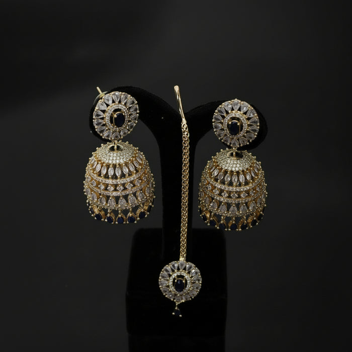 Gold and diamond earrings on a black stand with 'Saheli' branding.