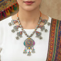 Decorative necklace with colorful pendants on a gray background, featuring the brand 'Saheli'.