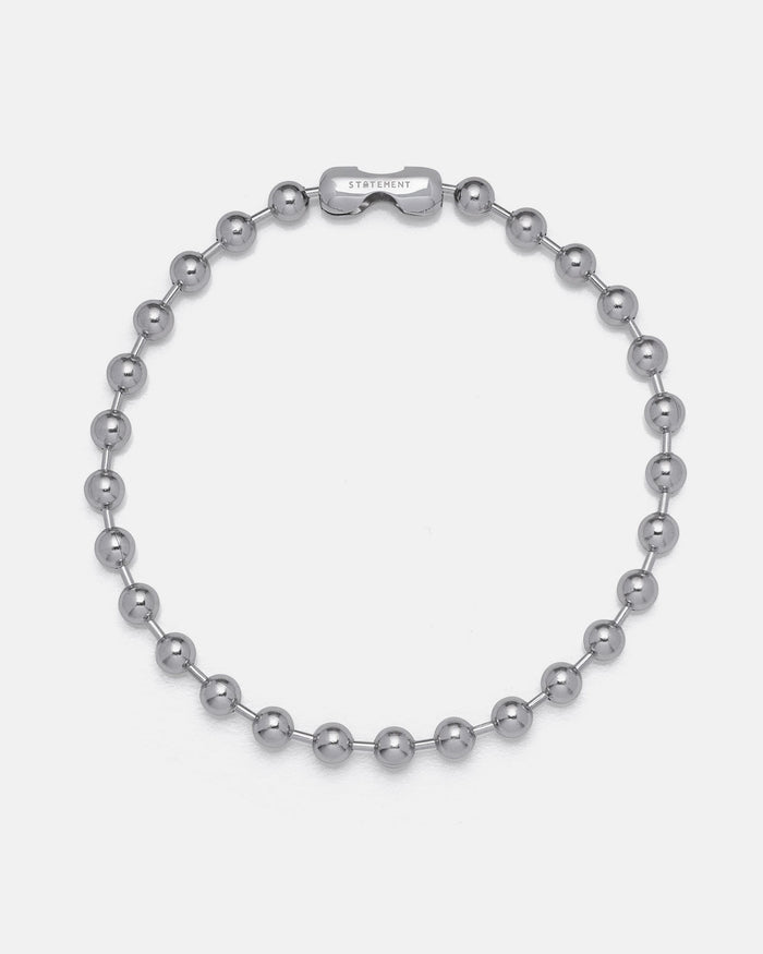 The No Tourists Choker is a silver beaded necklace with round, polished metal beads in a ball chain style and a rectangular STATEMENT-engraved clasp, shown on a plain white background.