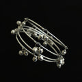 Set of silver anklets with small bells on a dark gray stand, brand 'Saheli' visible.