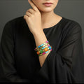 Colorful beaded bracelets on a gray cushion against a dark background