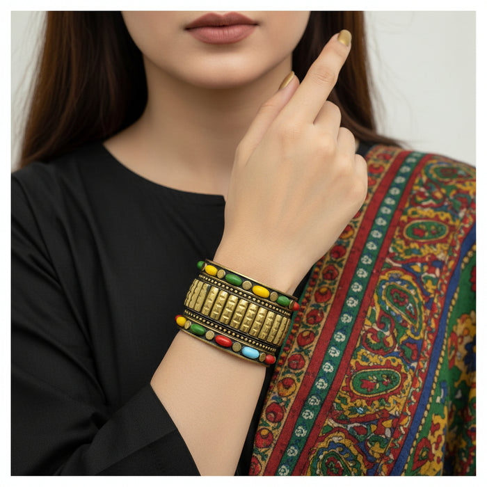 Gold bracelet with colorful beads on a gray stone surface
