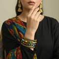 Set of colorful beaded bracelets on a gray stand against a dark background