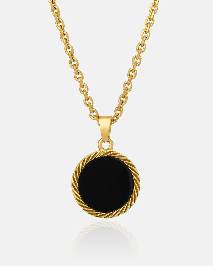 The Onyx Medallion Pendant (Gold) is a gold chain necklace with a round black agate onyx pendant and a twisted gold border, shown against a plain white background.
