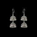Silver earrings on a gray stand with 'Sahell' branding.