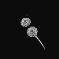 Silver floral earrings on a gray cushion with a dark background
