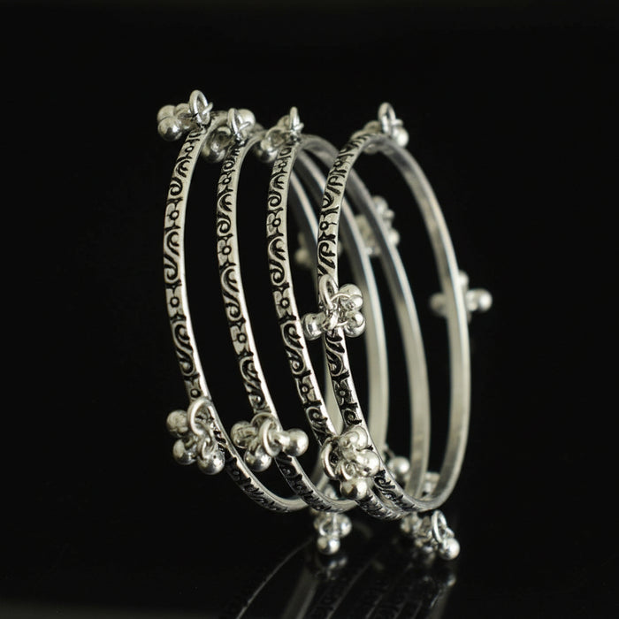 Set of silver hoop earrings on a black stand against a gray background