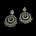 Pair of silver earrings with intricate designs on a black background