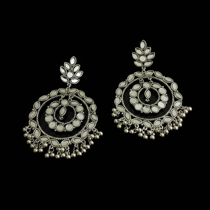 Pair of silver earrings with intricate designs on a black background