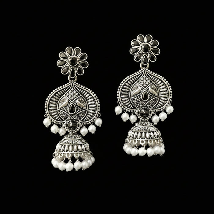 Pair of silver earrings with floral designs and pearl beads on a gray background