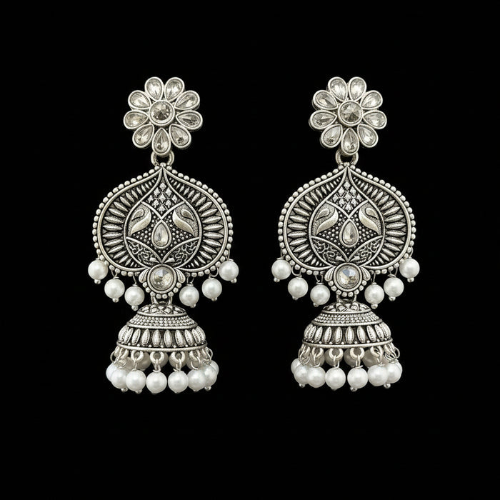 Pair of silver floral earrings with pearl beads on a gray stand.
