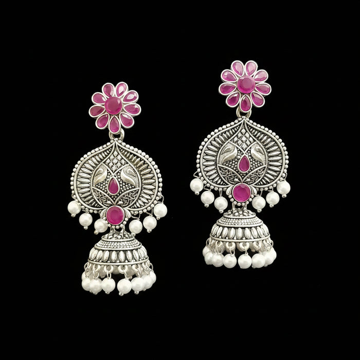 Ornate silver earrings with pink gemstones and pearl-like beads on a gray stand.