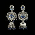 Pair of silver and blue earrings on a gray stand with a blurred background