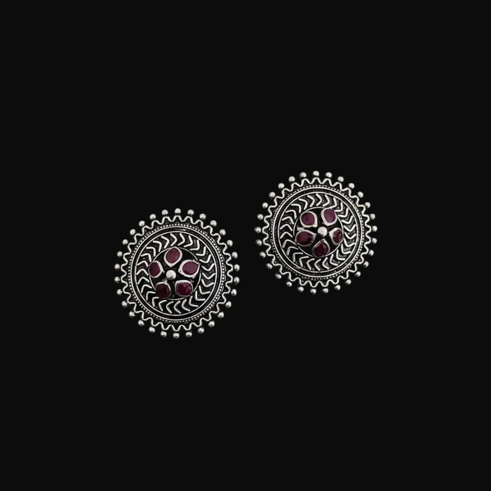 Pair of silver earrings with pink gemstones on a dark surface