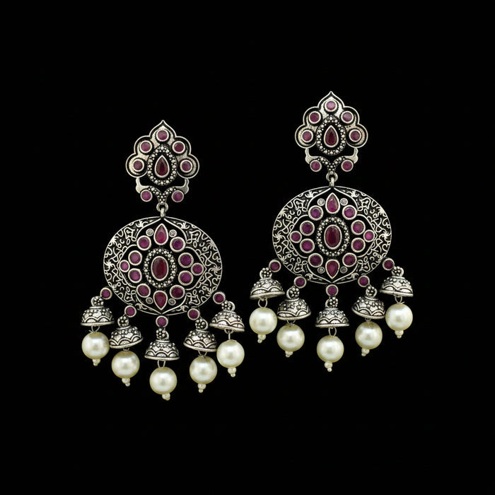 A pair of ornate silver-toned Indian jhumka earrings with pink stone accents and white pearl drops, displayed on a black Y-shaped stand against a gray background with an HP logo partially visible.