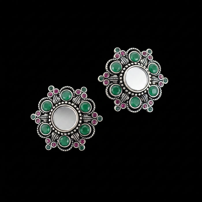 Pair of silver earrings with green and pink gemstones on a gray background