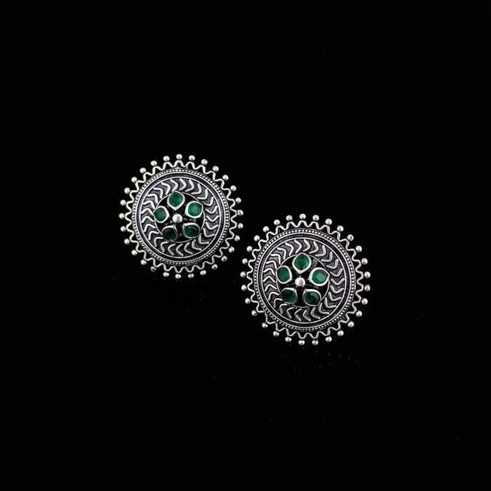 Pair of silver earrings with green gemstones on a dark surface