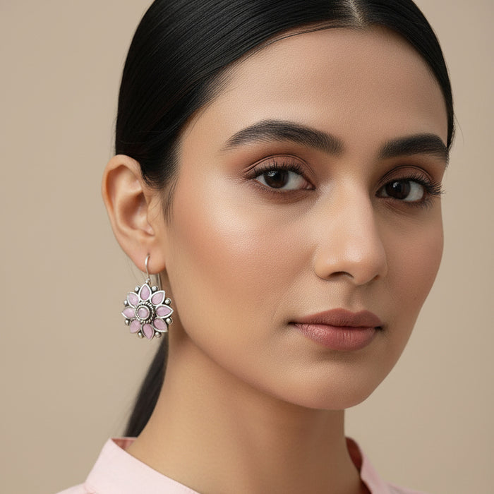 Pink flower-shaped earrings on a gray stone surface