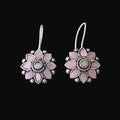 Pink flower-shaped earrings on a gray stone surface