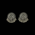 A pair of ornate silver-toned Indian jhumka earrings with intricate filigree work, floral motifs, and dangling bead chains, displayed on a dark reflective surface.