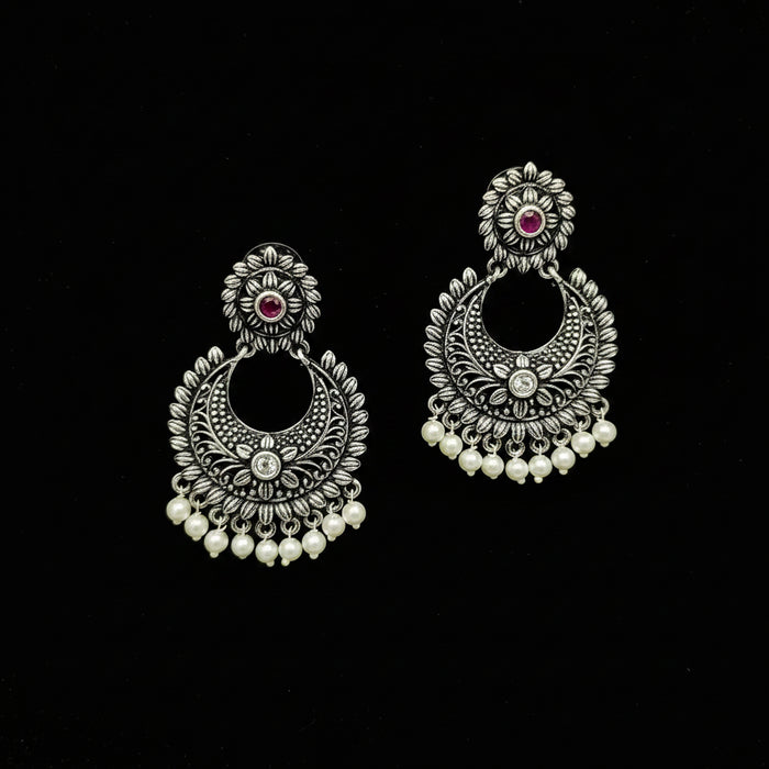 Pair of silver earrings with pearls and gemstones on a black background