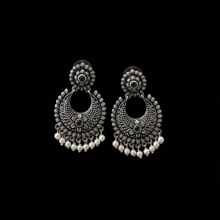 Pair of silver earrings with green stones and pearl-like beads on a gray background, branded 'Saheeli'.
