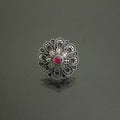 Decorative ring with a red gemstone on a dark gray background
