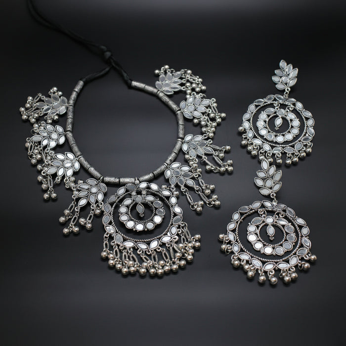 Silver necklace and earrings on a dark background