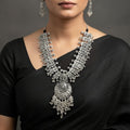 Silver necklace and earrings on a dark surface