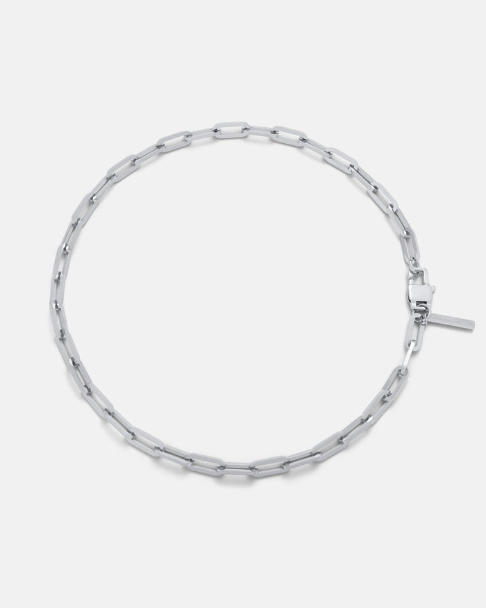 The Paperclip Chain is a silver necklace with elongated rectangular links and a simple clasp, shown in a circular shape on a white background—an ideal men’s accessory featuring an adjustable chain for the perfect fit.