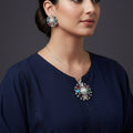 Three silver pendants with colorful gemstones on a dark background
