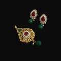 Ornate earrings with red and green stones on a gray background, featuring the brand 'SAHELI'.