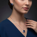 Jewelry set with necklace and earrings featuring blue gemstones on a black background, branded 'SAHELI'.