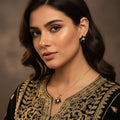 Pair of flower-shaped earrings with black and gold details on a gray background, branded 'SAHELI'.