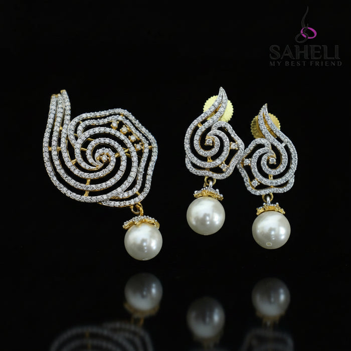 Ornate earrings with pearls on a dark background, featuring the brand 'Saheli'.