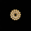 A gold flower-shaped ring with clear kundan stones and a central black stone, displayed on a reflective gray surface. The brand logo 'SAHELI MY BEST FRIEND' is visible in the top left corner.