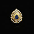 A gold teardrop-shaped ring with a central deep blue teardrop gemstone and surrounding clear rhinestones, displayed on a reflective gray surface. The brand logo 'SAHELI MY BEST FRIEND' is visible in the top left corner.