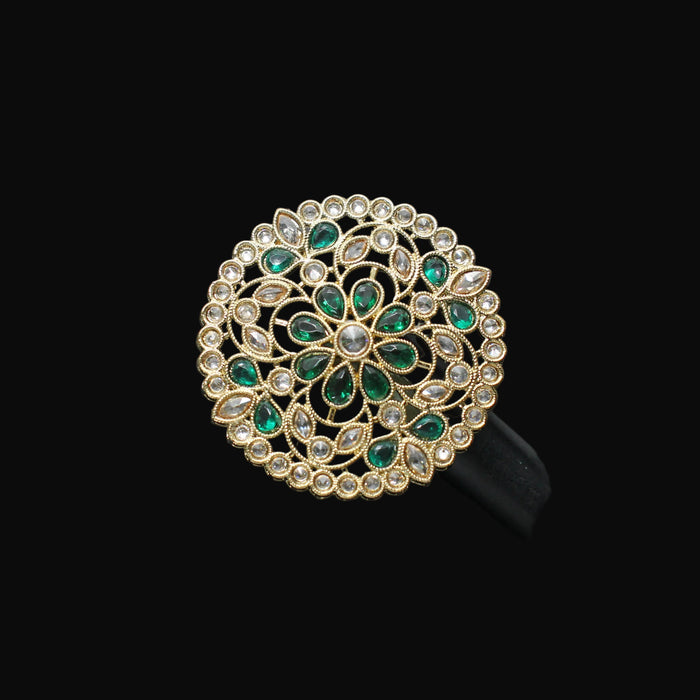 Decorative ring with green gemstones on a black mannequin hand against a dark background