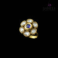 Gold ring with a blue gemstone on a gray background, branded 'Saheli'.
