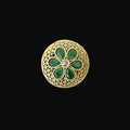 Gold ring with green gemstones on a black hand model