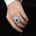 Teardrop-shaped diamond earring with black gemstone on a reflective surface, branded 'Saheli'.