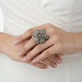 Decorative brooch on a black fabric background with 'SAHELI' branding.
