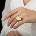 Gold and diamond ring on a gray background with 'Saheli' branding.