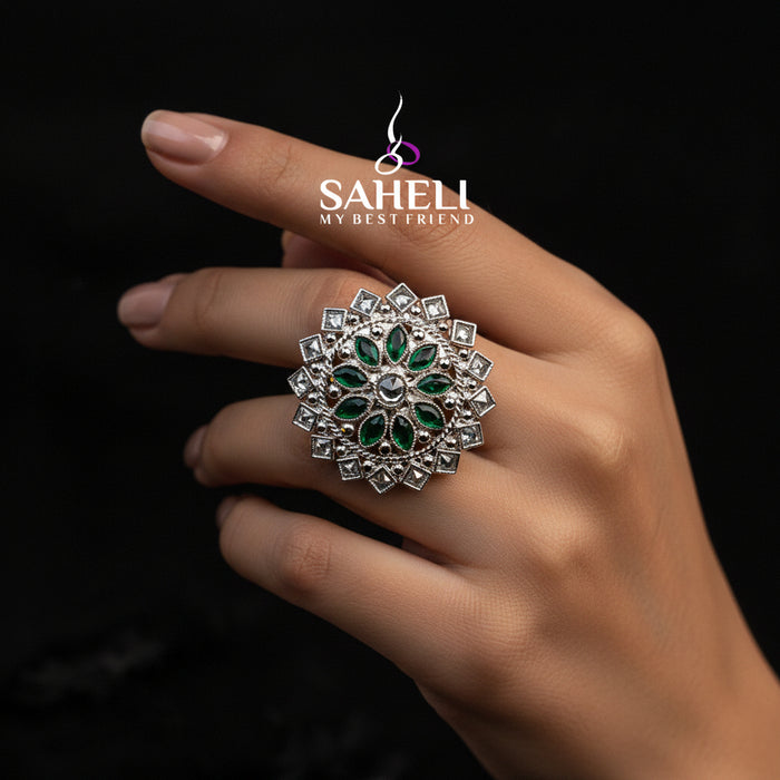 A large silver-toned floral ring with green stone accents is displayed on a black velvet hand against a dark background, with the brand name SAHELL MY BEST FRIEND printed above.