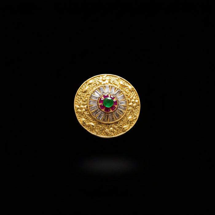 A large gold-toned statement ring displayed on a black mannequin hand. The ring features an intricate circular design with a central red and green motif surrounded by clear stones, set against a dark gray background with a 'SAHELL' watermark in the top left corner.