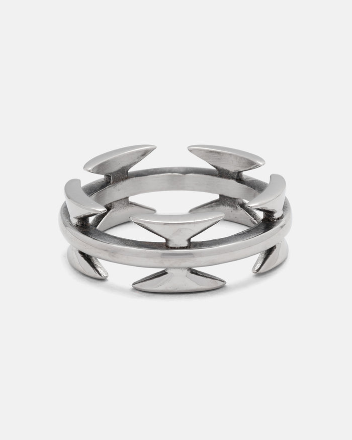 Introducing the Razor Wire Ring by Statement Collective—a silver ring with dual bands adorned with evenly spaced, outward-facing arrowhead shapes, forming a modern geometric design. This razor wire ring offers an edgy accent to any streetwear jewelry collection.
