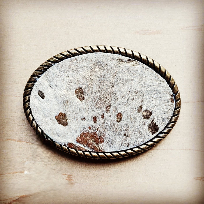 Oval belt buckle faced in white spotted hair on hide with an antique gold rope edge