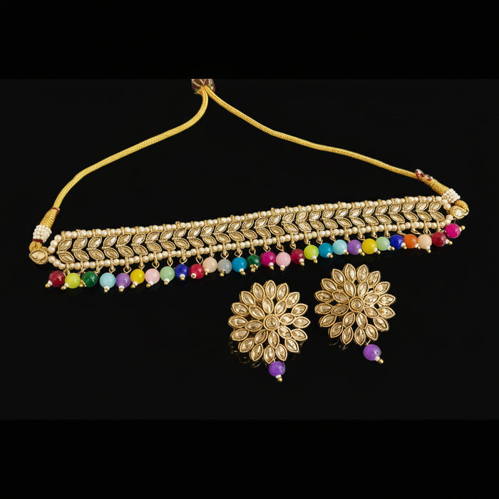 Gold necklace with colorful beads and matching earrings on a dark surface