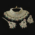 Ornate gold necklace set with green and red stones on a dark background, featuring the brand 'Saheli'.